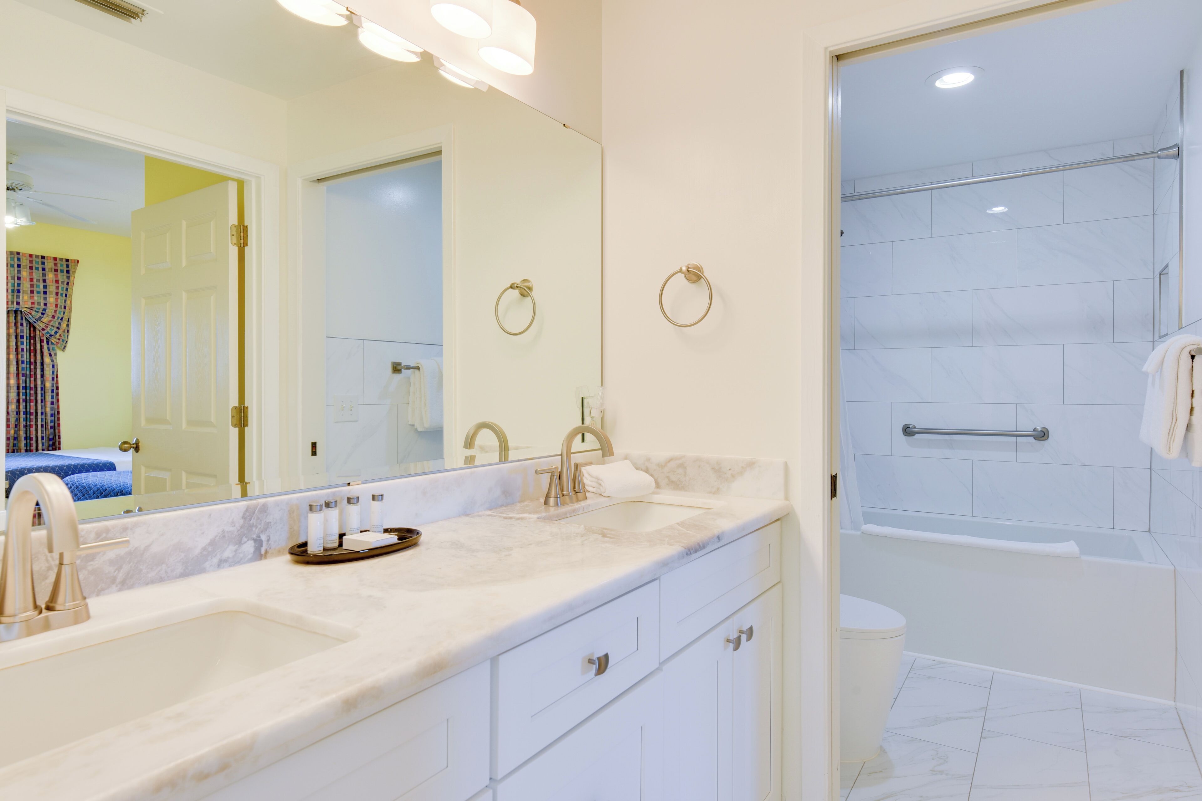 A bathroom with a double sink, a large mirror, a shower with a glass door, and a toilet.
