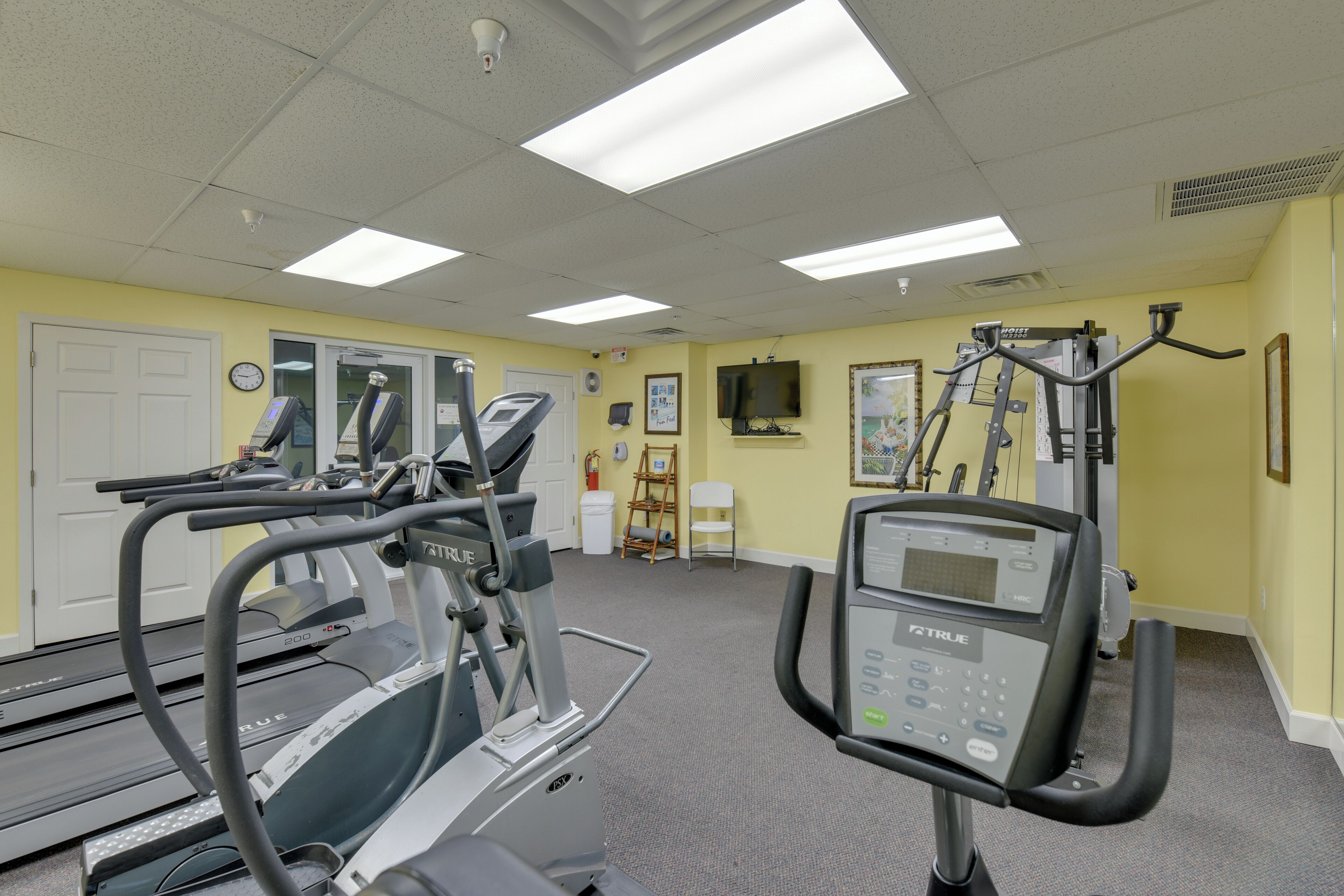 Ein Fitnessstudio mit Laufbändern, Crosstrainern und Krafttrainingsgeräten.
