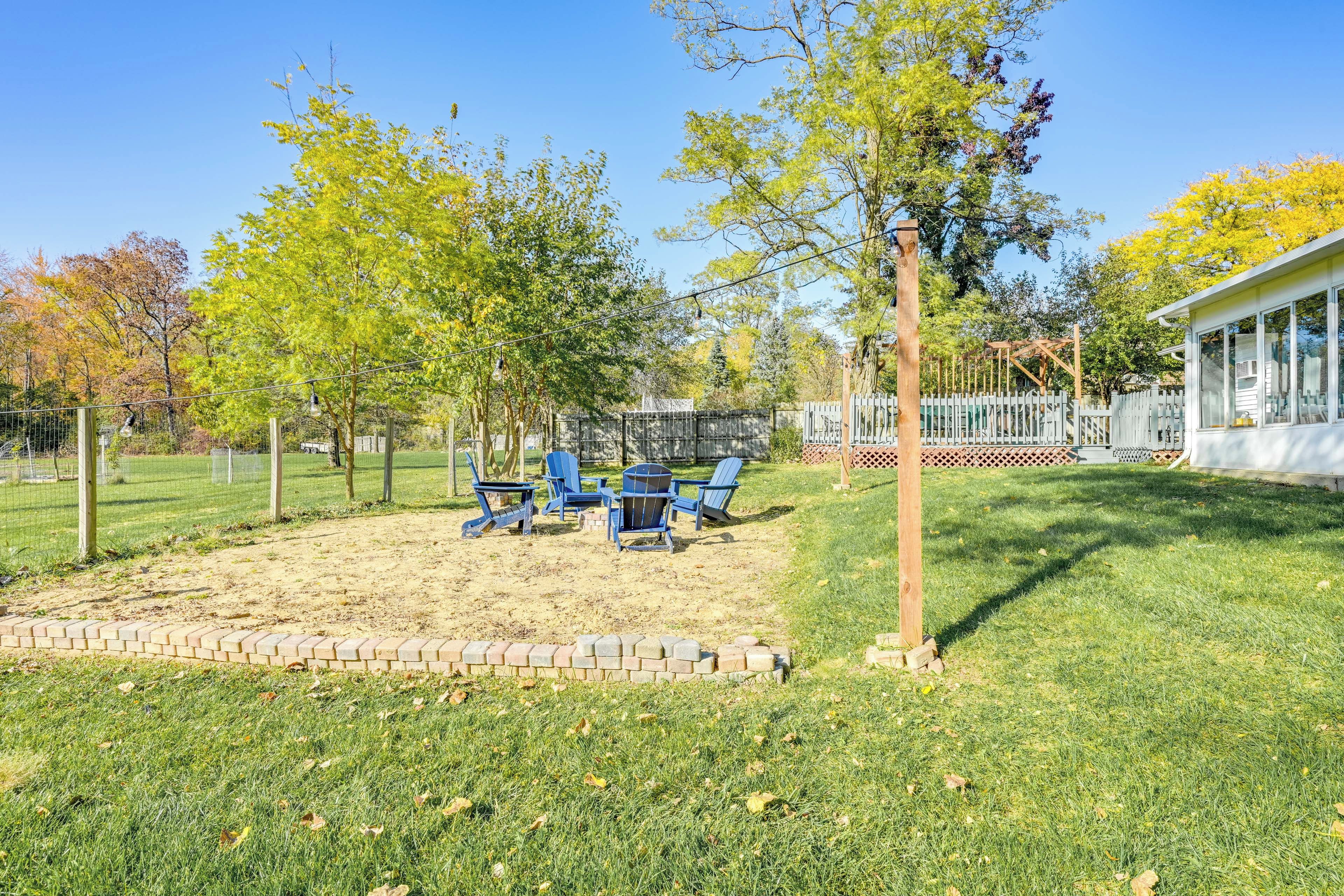 Ein Garten mit einer Terrassenfläche, Gartenmöbeln und einem umzäunten Spielbereich.