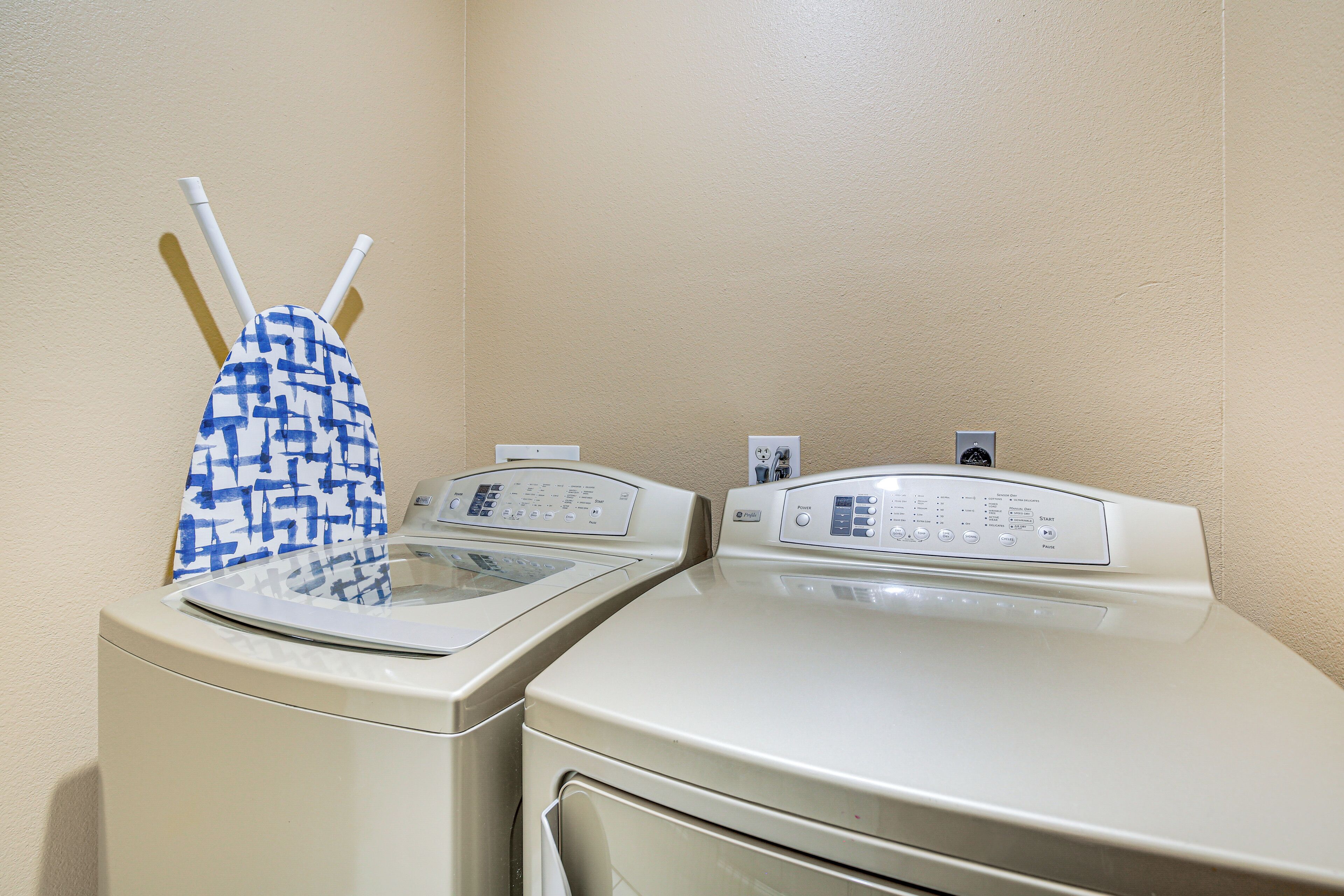 A laundry area with two washing machines and a blue and white patterned towel hanging on the wall.