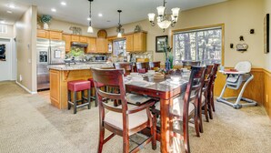 A spacious kitchen with wooden cabinets, a large island, and a dining area with a high chair.