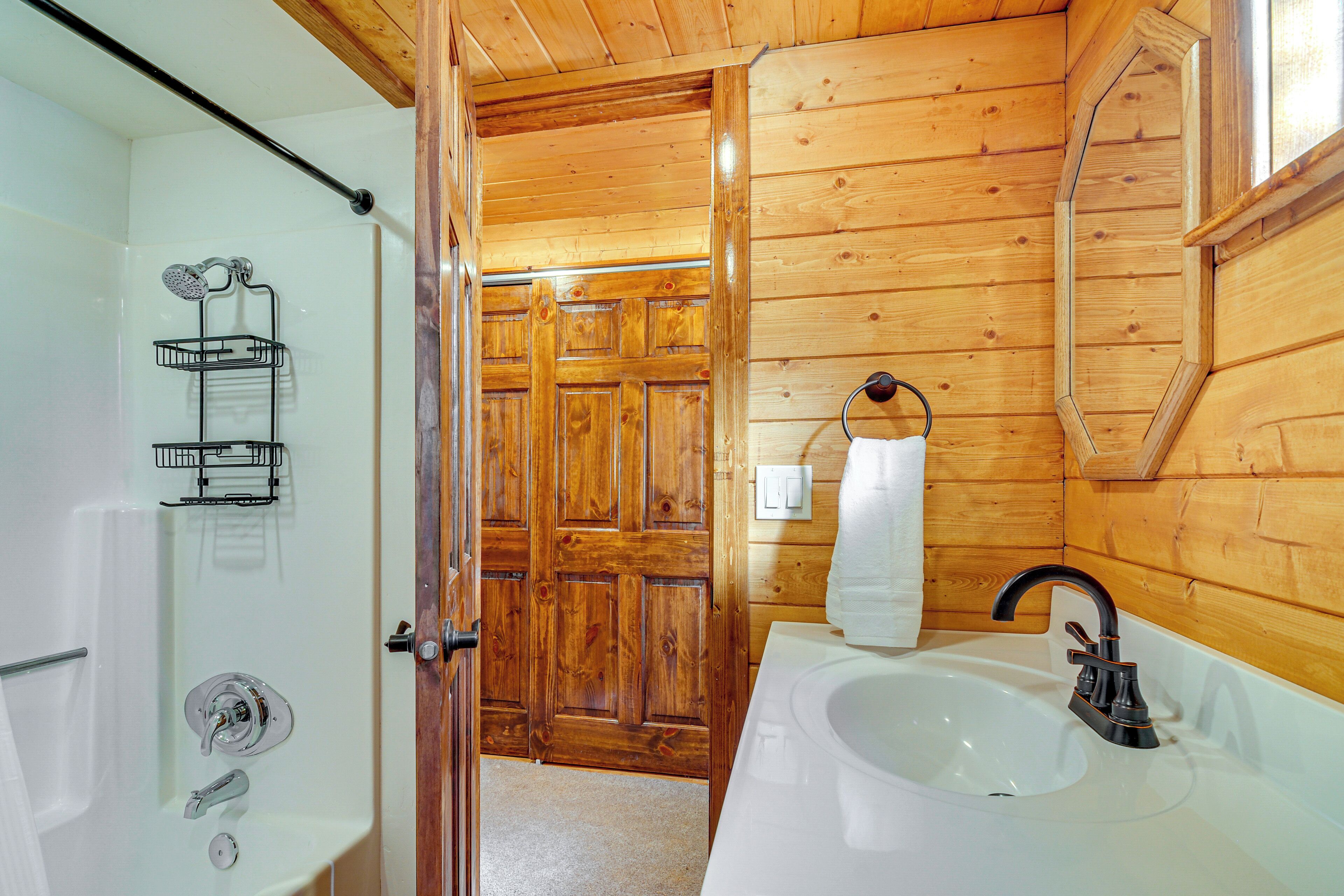 Une salle de bain avec un intérieur en bois, une baignoire blanche, un lavabo avec un robinet noir et un espace douche doté d’une porte en verre.