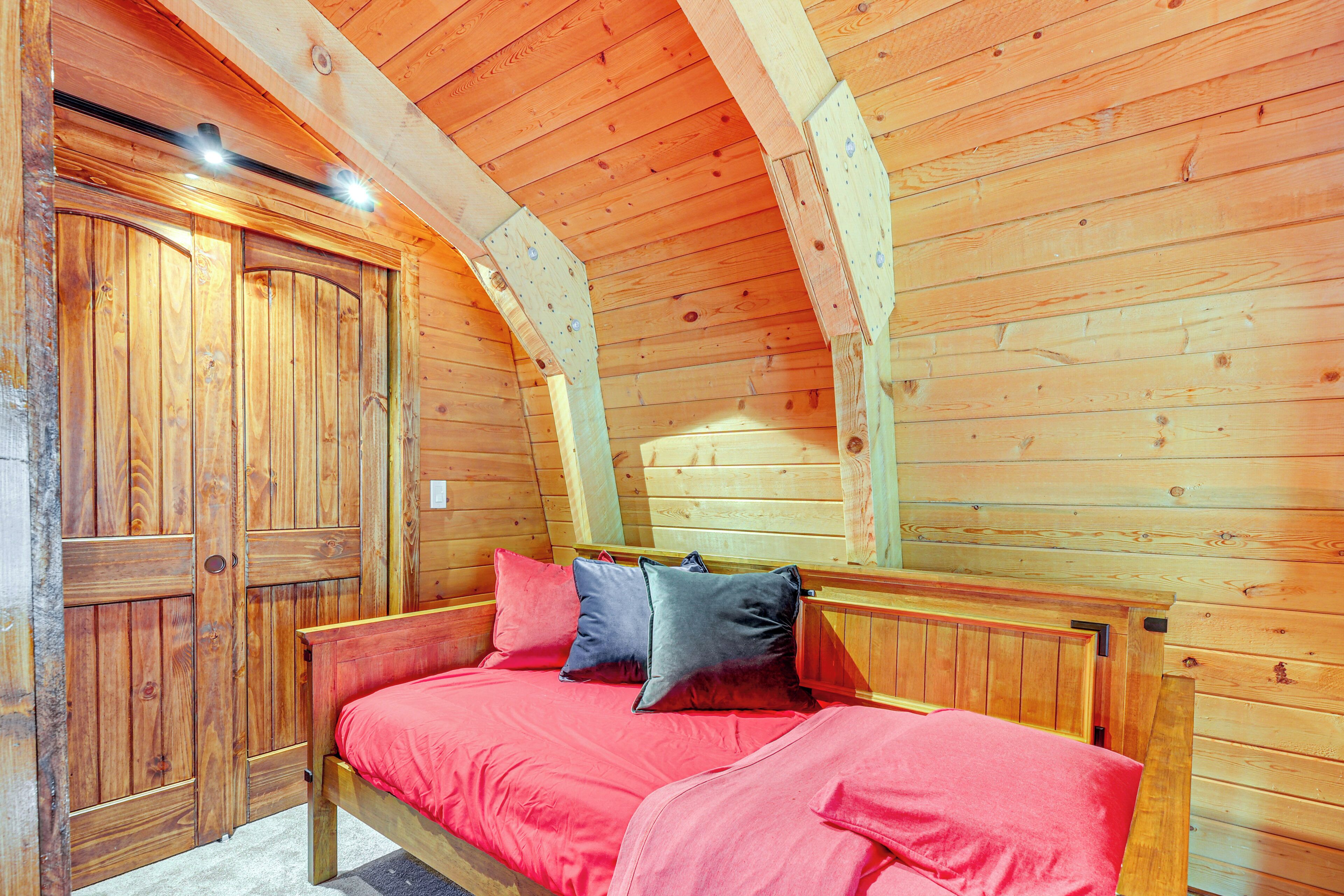Ein Holzhüttenraum mit einem Bett, einer Holztür und einer schrägen Decke.