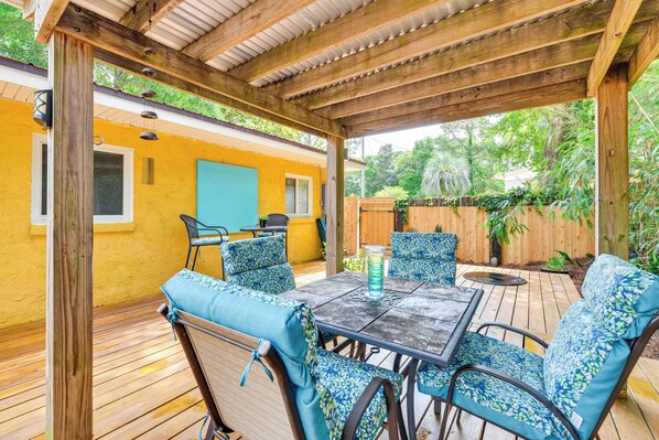 Eine Außenpatio mit einer Holz-Pergola, einem Tisch mit Stühlen und einer blauen Tür im Hintergrund.