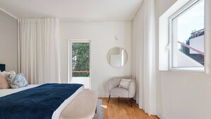 A bedroom with a bed, a chair, a round mirror, and a window. - Acm021 Bombarda Homes, Spacious 3BR for Families (Porto)