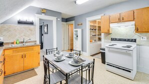 A kitchen with wooden cabinets, a white stove, and a dining table set with plates and bowls. - < 2 Mi to Hospitals & University: South Wedge Apt! (Rochester)