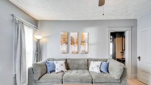 A living room with a grey sofa, patterned cushions, a floor lamp, and three paintings on the wall. - < 2 Mi to Hospitals & University: South Wedge Apt! (Rochester)