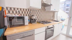 A compact kitchen with a microwave, coffee maker, and gas stove.