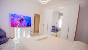 A modern bedroom with a bed, a TV, a wardrobe, and a mirror.