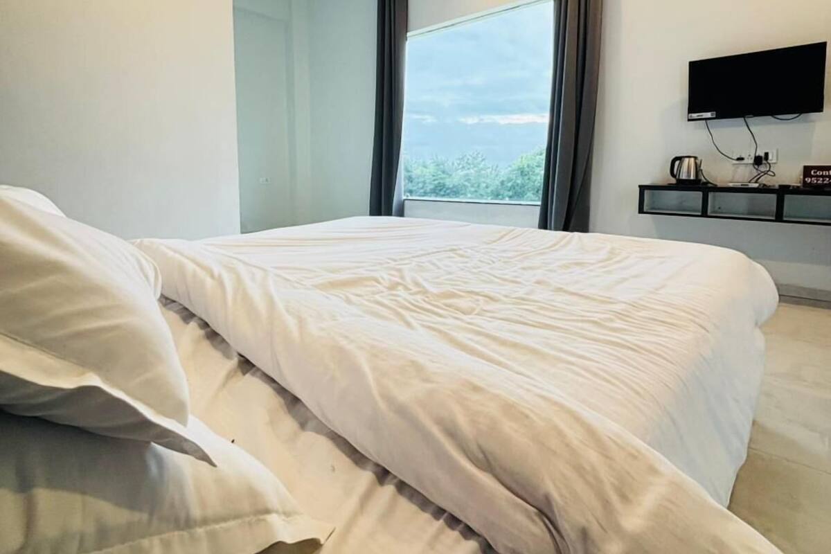 Een moderne hotelkamer met een groot bed, een flatscreen televisie en een raam met gordijnen.