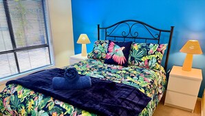 A bedroom with a bed, two nightstands, a window with blinds, and a blue wall. - Lakeside Getaway - 4BR Jetty Wi-fi Waterfront (Encounter Bay)