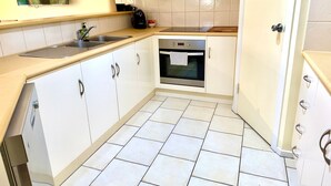 A kitchen with white cabinets, a built-in oven, a microwave, and a sink. - Lakeside Getaway - 4BR Jetty Wi-fi Waterfront (Encounter Bay)