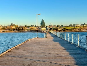 A wooden pier extending into a body of water, with a metal railing on one side and a streetlight on the other.