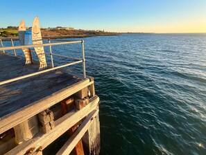 A wooden pier extending into calm waters with a clear sky.