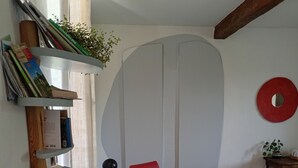 A living room with a green armchair, a red chair, a bookshelf, and a coffee table.