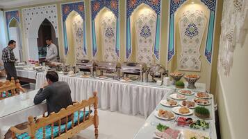 A buffet setup with food items and a person serving.