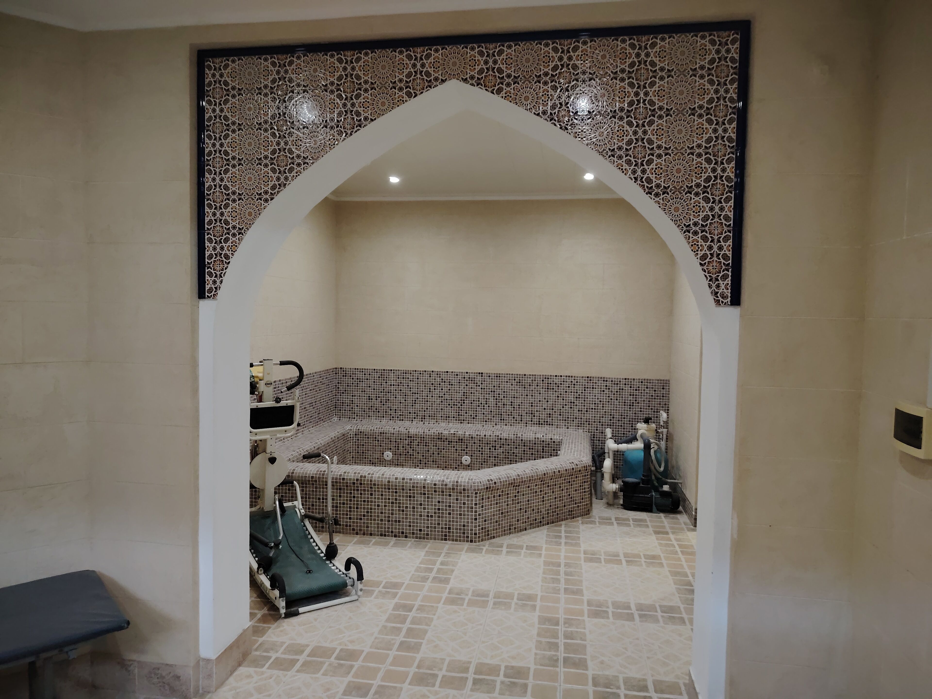 Une salle de spa dotée d’une baignoire ornée de mosaïques, d’un fauteuil de massage et d’un banc.