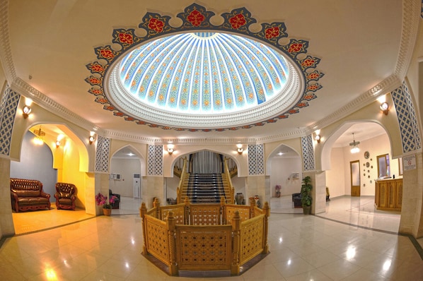 A grand lobby with a central staircase, ornate ceiling, and seating area. - Minorai Kalon Hotel (Bukhara)