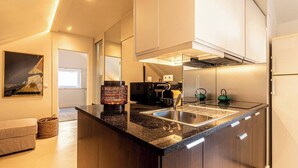 Una cocina moderna con encimeras oscuras, electrodomésticos de acero inoxidable y horno empotrado.