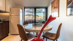 Una cocina compacta con refrigerador, una mesa de comedor con cuatro sillas y un amplio ventanal con vistas a la ciudad.