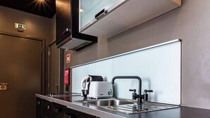 A modern kitchen with dark wood cabinets, a stainless steel countertop, and a built-in dishwasher. - Well-located Studio with Smart Space (Lisbon)