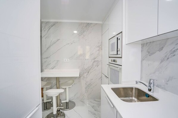 Een koelkast, een kookplaat, kookgerei, borden en bestek