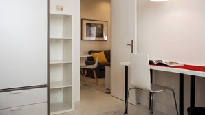 A modern, well-lit room with a desk, chair, and a bookshelf.