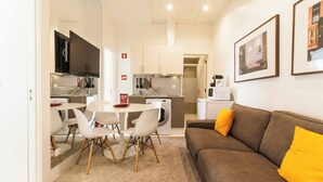 A compact living space with a dining area, kitchenette, and a sofa with yellow cushions.