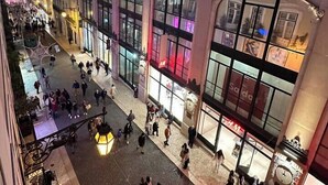 A busy urban square with historic buildings, large glass windows, and people walking.