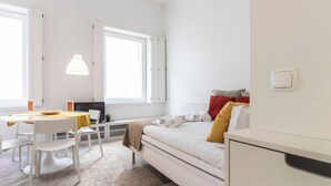 A modern, minimalist bedroom with a bed, a desk, and a chair.