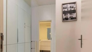 A hallway with a mirrored closet, a framed picture on the wall, and a bathroom visible in the distance.