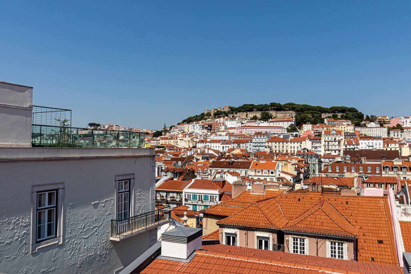 Eine Stadtansicht mit Blick auf eine Hügelburg und dicht bebauten Häusern mit roten Ziegeldächern.