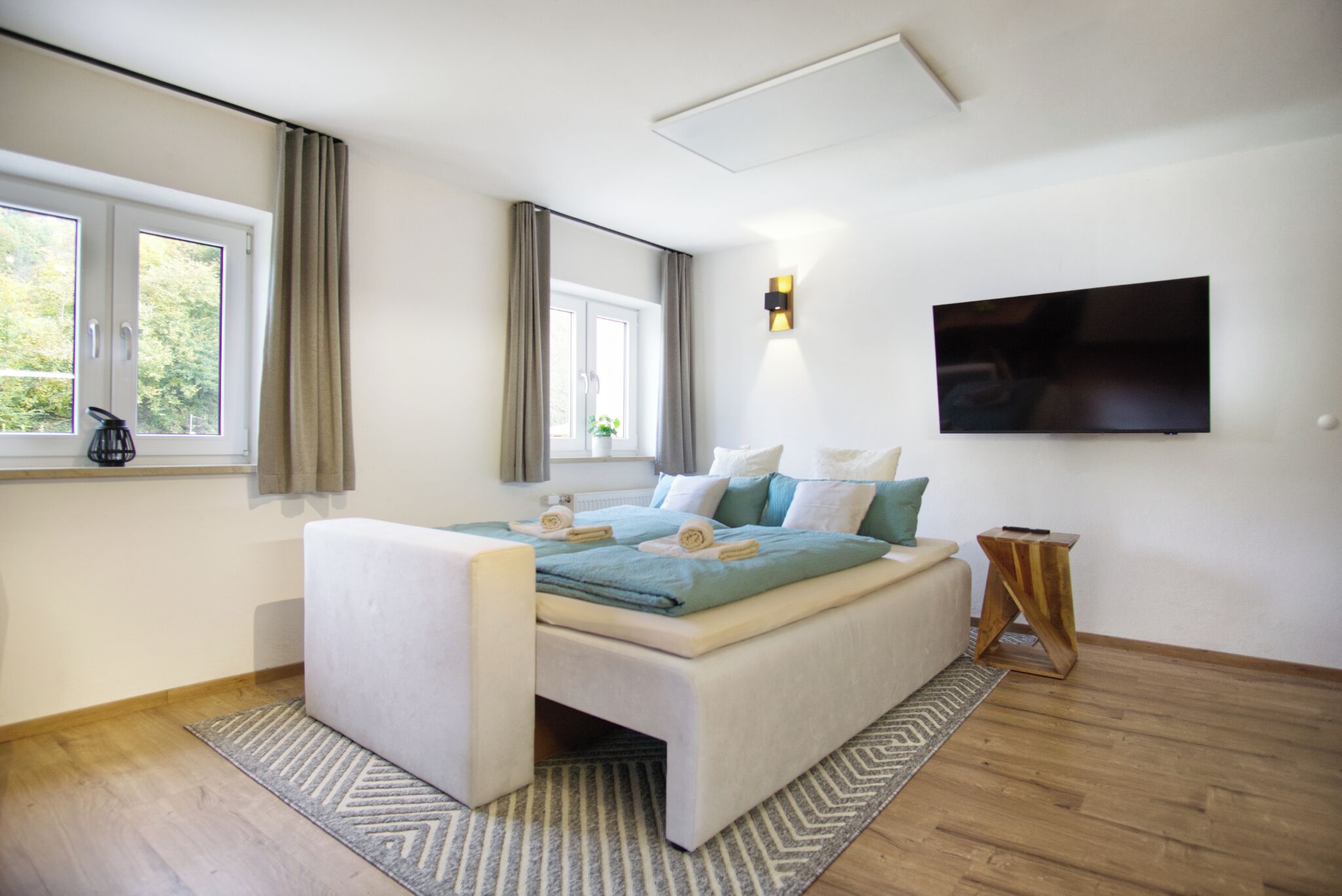 Ein modernes Schlafzimmer mit einem Bett, einem Fernseher und einem Fenster.