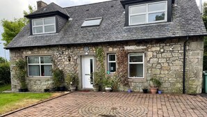 A stone house with a tiled driveway and potted plants.