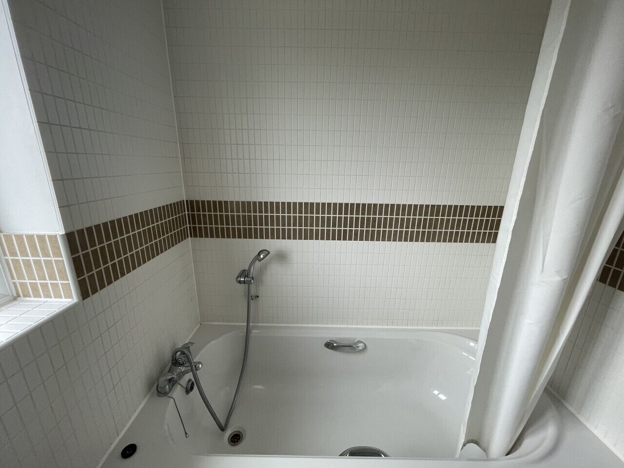 A bathroom with a bathtub, shower, and tiled walls.