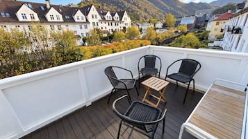 Une terrasse avec quatre chaises et une petite table, d’où l’on peut admirer une ville avec ses maisons et ses montagnes.