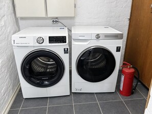 Two front-loading Samsung washing machines with digital interfaces, placed next to a fire extinguisher on a tiled floor. - Quiet place near city centre and the mountains (Vestland)