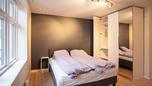Un dormitorio moderno con cama, mesita de noche y un espejo grande.