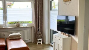 Una sala de estar moderna con un sofá, un televisor y un mueble bajo.
