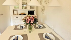 Una mesa de comedor dispuesta con platos, cubiertos y un jarrón de flores.