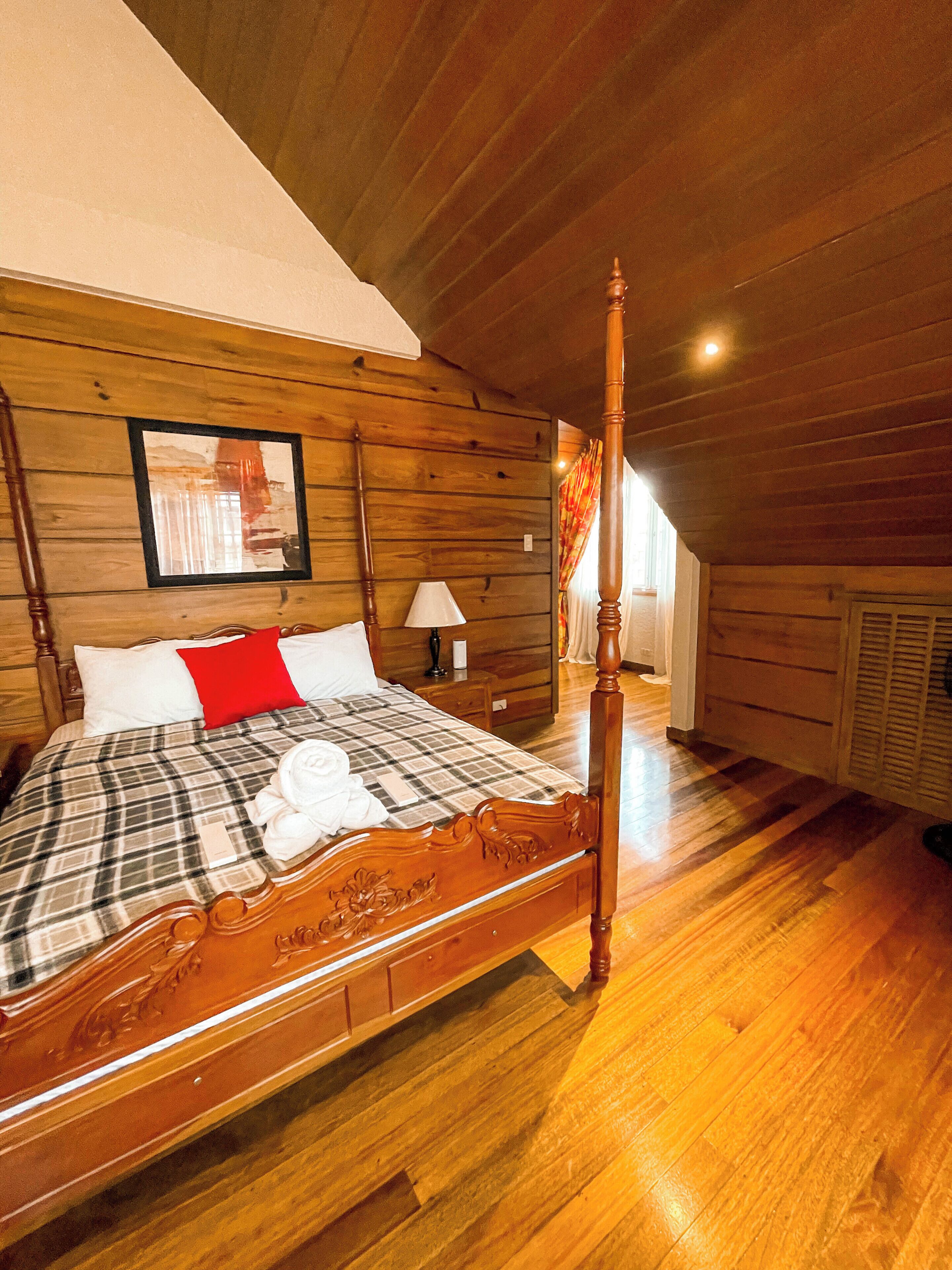 Ein Raum mit Holzwänden und schrägem Dach, ausgestattet mit einem Himmelbett.