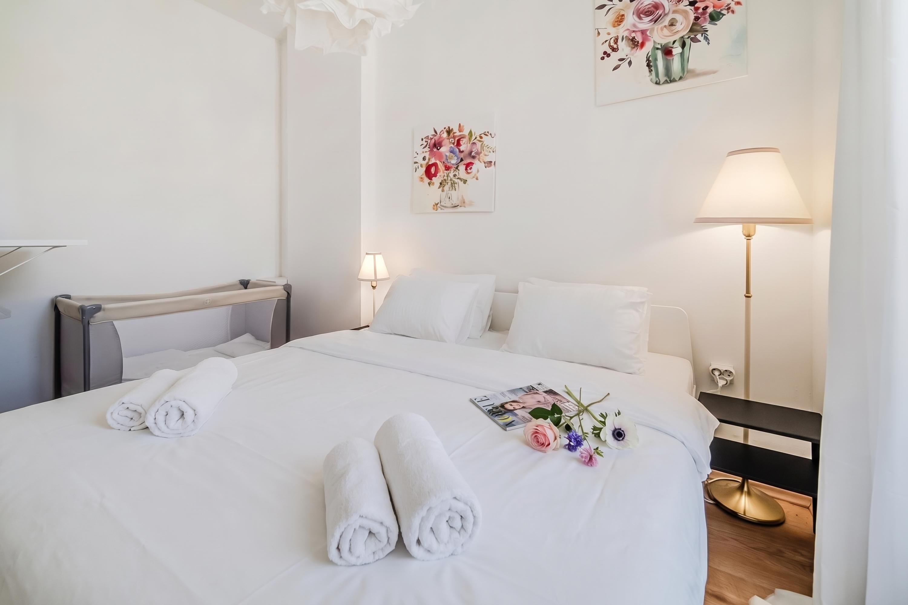Una habitación de hotel con una cama bien hecha, una mesita de noche con lámpara y una obra de arte colgada en la pared.