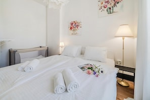 Habitación de hotel con una cama bien hecha, dos lámparas de noche, una mesita de noche y una obra de arte en la pared.