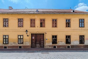 A yellow building with a tiled roof, multiple windows, and a large wooden door. - Old Town Heritage Suites (Osijek)