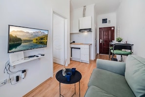 A compact living space with a TV, kitchenette, and seating area. - Old Town Heritage Suites (Osijek)