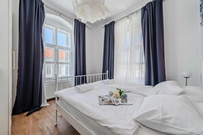 Une chambre à coucher avec un lit, des rideaux, une fenêtre et un radiateur.