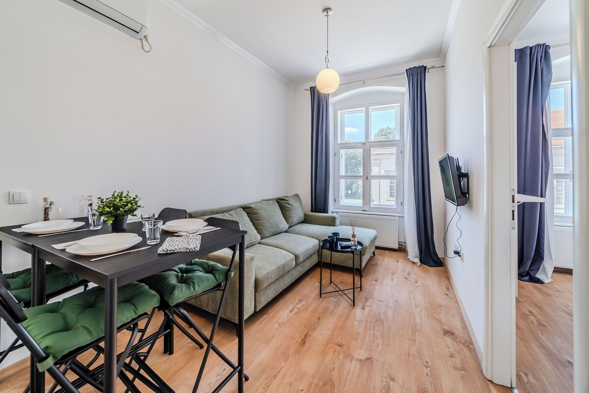 Ein modernes Wohnzimmer mit Esstisch für vier Personen, einer Couch und einem kleinen Beistelltisch.