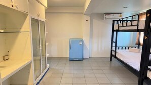 Ein Schlafraum mit Etagenbetten, einem kleinen, blauen Kühlschrank und einem Schrank mit Glastüren.