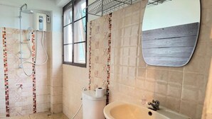 Ein Badezimmer mit Dusche, Toilette, Waschbecken und einem Fenster.