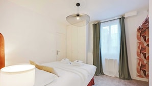 Ett hotellrum med en säng, en sänglampa, ett fönster med gardiner och en vägg med ett geometriskt mönster.